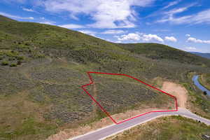 Aerial view of property and surrounding area with property parcel outlined and a mountainous background