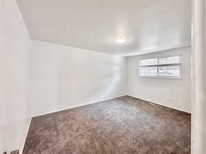 Carpeted empty room with baseboards and a textured ceiling