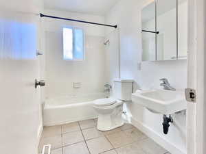 Full bath with shower / washtub combination and light tile patterned floors