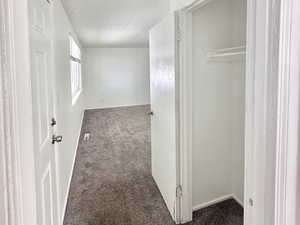 Hall with dark colored carpet and a textured ceiling