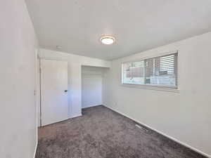 Unfurnished bedroom with carpet flooring, a textured ceiling, and a closet