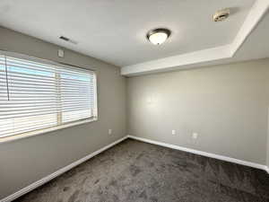 Unfurnished room featuring carpet flooring, a smoke detector, and a textured ceiling