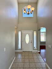 Tiled foyer entrance featuring arched walkways, a chandelier, and a towering ceiling