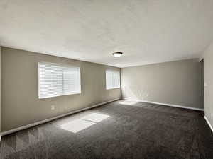 Spare room with dark colored carpet and a textured ceiling