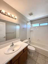 Bathroom with vanity, washtub / shower combination, tile patterned floors, and a textured ceiling