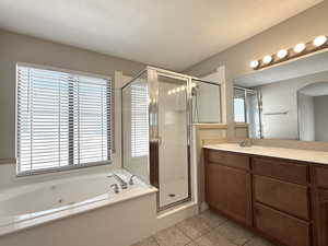 Bathroom with a jetted tub, a shower stall, healthy amount of natural light, and tile patterned flooring