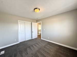 Unfurnished bedroom with dark carpet and a closet
