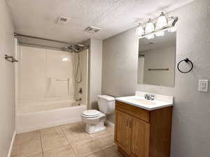 Bathroom with a textured wall, vanity, shower / bathtub combination, tile patterned flooring, and a textured ceiling