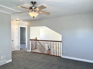 Carpeted empty room with a ceiling fan and baseboards