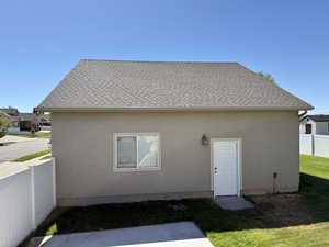 Back of property featuring roof with shingles and stucco siding