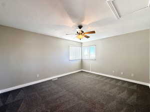 Unfurnished room featuring ceiling fan and dark carpet
