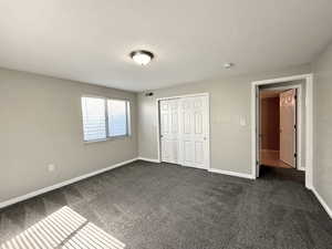 Unfurnished bedroom featuring dark carpet and a closet
