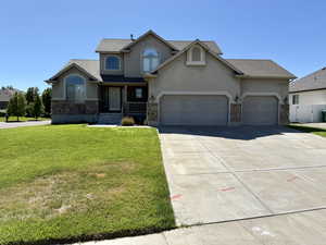 Traditional-style house featuring stucco siding, stone siding, concrete driveway, and a garage
