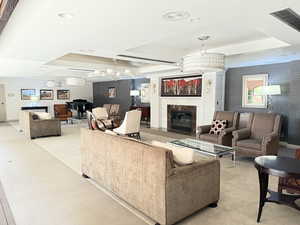 Living room featuring wallpapered walls, a fireplace, a chandelier, a raised ceiling, and recessed lighting