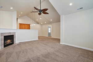 Unfurnished living room featuring a ceiling fan, light carpet, a fireplace, high vaulted ceiling, and recessed lighting