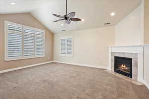 Unfurnished living room with vaulted ceiling, a ceiling fan, carpet floors, recessed lighting, and a tile fireplace