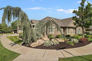 View of front of home with stucco siding, stone siding, and a shingled roof