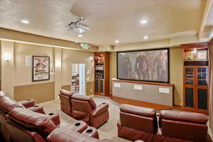 Carpeted cinema room with a textured ceiling and recessed lighting