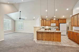 Kitchen with light carpet, lofted ceiling, white appliances, a peninsula, and ceiling fan