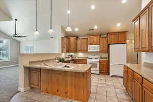 Kitchen featuring white appliances, vaulted ceiling, a peninsula, light countertops, and recessed lighting