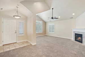 Carpeted foyer with vaulted ceiling, a ceiling fan, a tile fireplace, recessed lighting, and tile patterned flooring