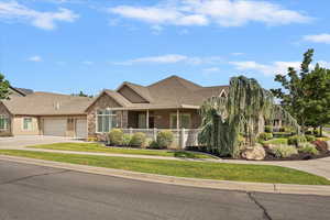 View of front of property featuring an attached garage, concrete driveway, stone siding, a porch, and roof with shingles