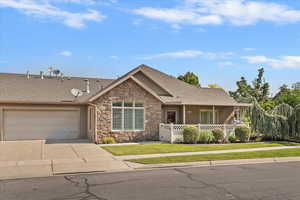 View of front of house with a shingled roof, concrete driveway, a garage, and stone siding