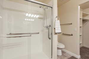 Bathroom with a stall shower, a spacious closet, and tile patterned floors