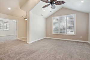 Carpeted empty room featuring ceiling fan, lofted ceiling, recessed lighting, and plenty of natural light