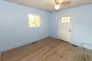 Entrance foyer featuring light wood-style flooring, ceiling fan, and wooden walls