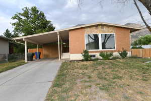 View of front facade with a carport, concrete driveway, and brick siding