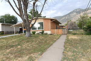 View of side of home with a mountain view, an attached carport, driveway, and brick siding