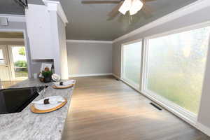 Living area with light wood-type flooring, ornamental molding, and ceiling fan