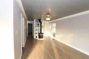 Unfurnished living room with ceiling fan, wood finished floors, and ornamental molding
