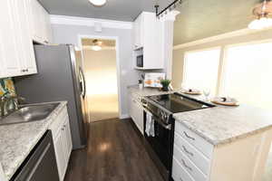 Kitchen with ceiling fan, electric range oven, dark wood-type flooring, dishwashing machine, and a peninsula