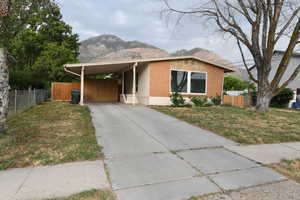 View of front of home featuring a carport, concrete driveway, a mountain view, and brick siding