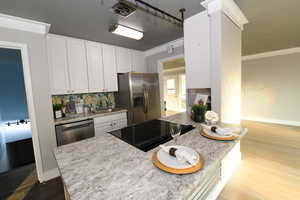 Kitchen featuring white cabinetry, appliances with stainless steel finishes, dark wood-type flooring, and tasteful backsplash