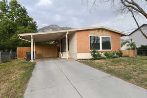 View of front of property with an attached carport, concrete driveway, a mountain view, and brick siding