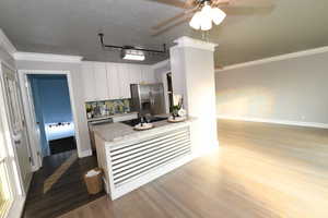 Kitchen with dark wood finished floors, appliances with stainless steel finishes, ceiling fan, backsplash, and white cabinetry