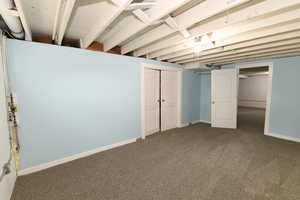 Finished basement featuring dark colored carpet and baseboards