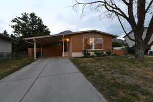View of front of property featuring concrete driveway, a carport, and brick siding