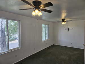 Spare room with ceiling fan and dark colored carpet