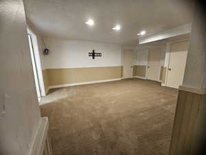 Carpeted empty room with recessed lighting, a textured ceiling, and a wainscoted wall