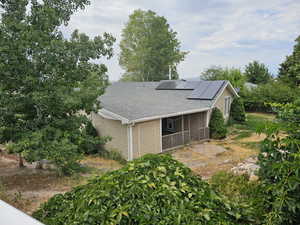 View of home's exterior with roof mounted solar panels and a shingled roof