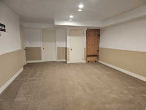 Below grade area featuring carpet floors, a wainscoted wall, crown molding, and recessed lighting