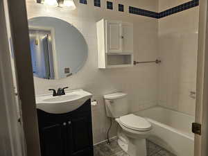 Bathroom featuring vanity, tile walls, tile patterned floors, and shower / bathtub combination