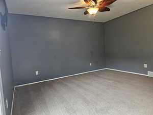 Carpeted empty room featuring ceiling fan and baseboards