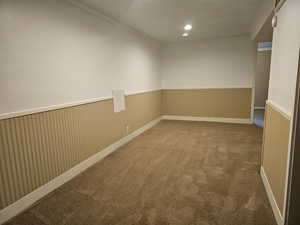 Empty room with wainscoting, carpet flooring, and ornamental molding