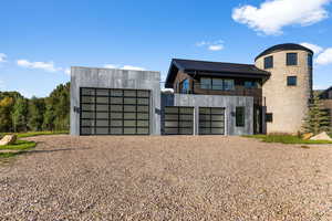 Modern home with a balcony, a metal roof, and a garage