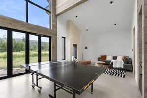 Rec room featuring high vaulted ceiling, beam ceiling, and concrete flooring